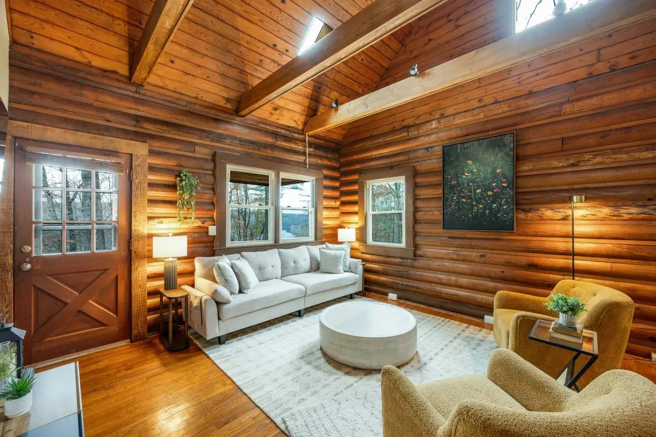 Log cabin living room with a beamed ceiling, cream sofa and wildflower art print
