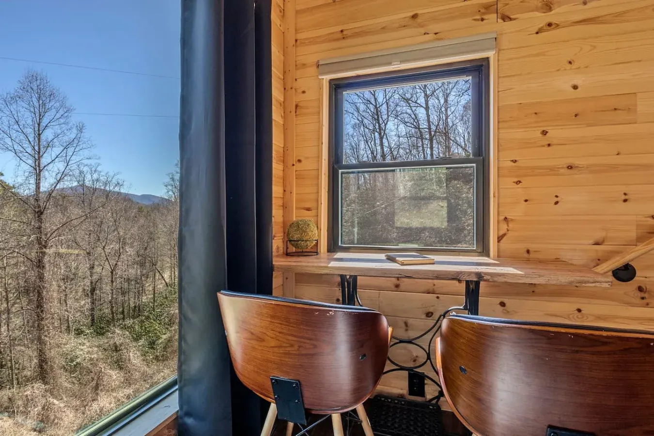 Window nook with a writing desk, two chairs and a mountain view