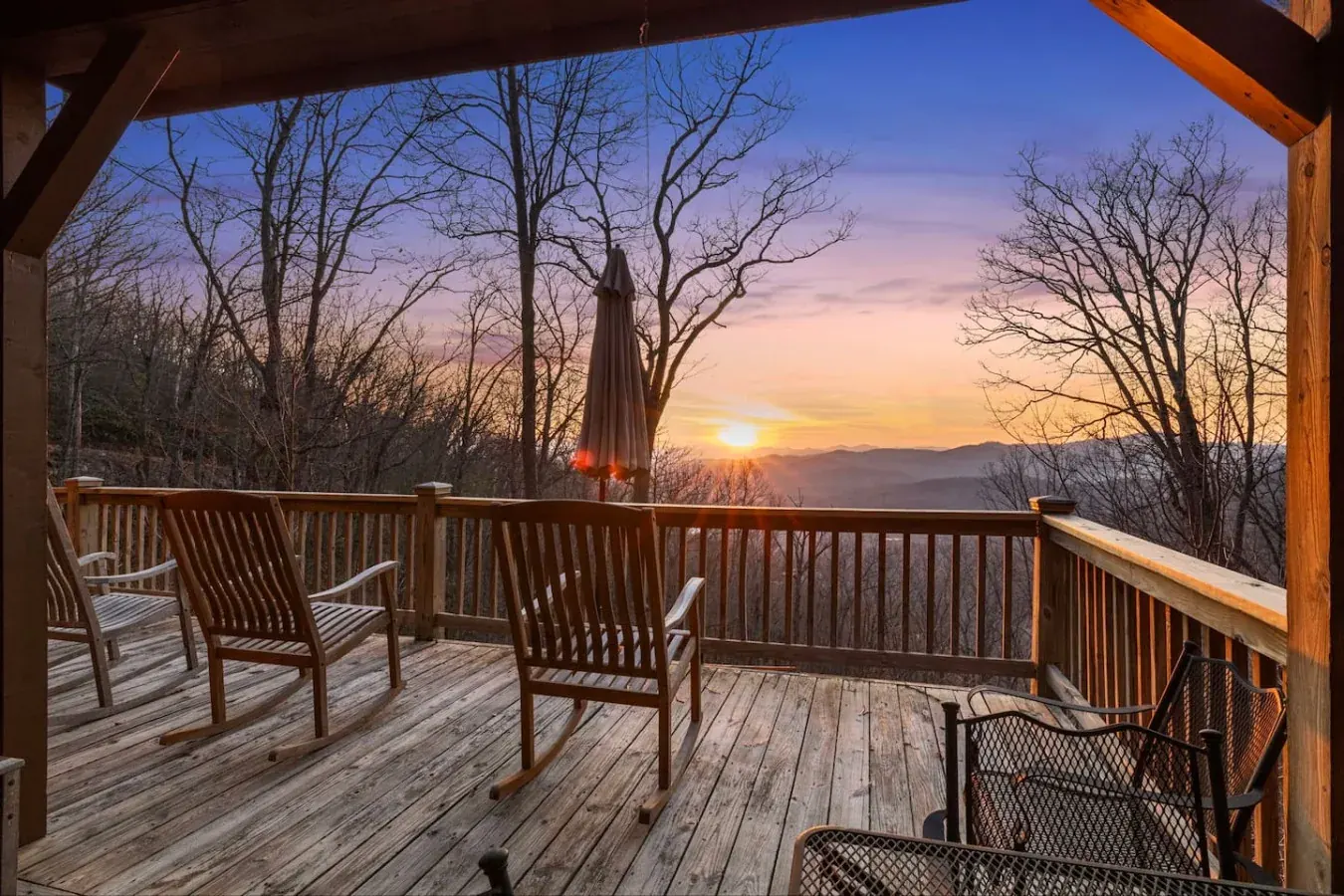 Covered deck with rocking chairs overlooking a mountain sunset