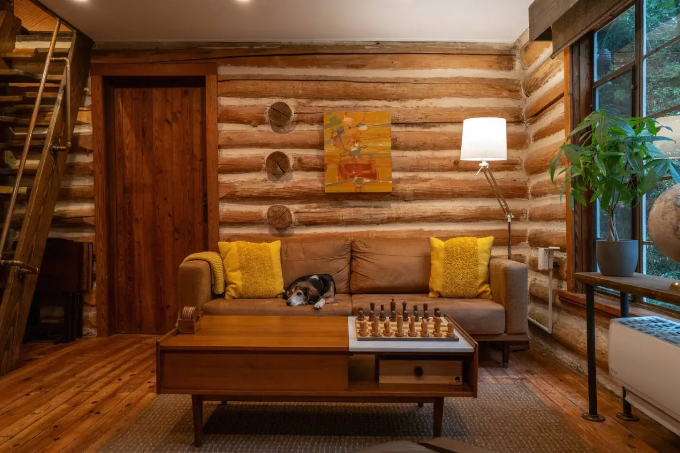Log cabin living room with a leather sofa, chess set and a dog resting on the cushions
